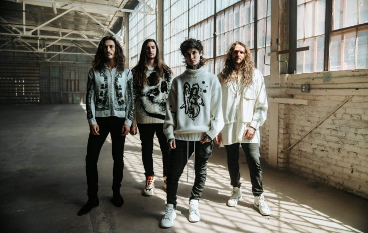 Les 4 membres de polyphia dans un bâtiment qui a l'air sale